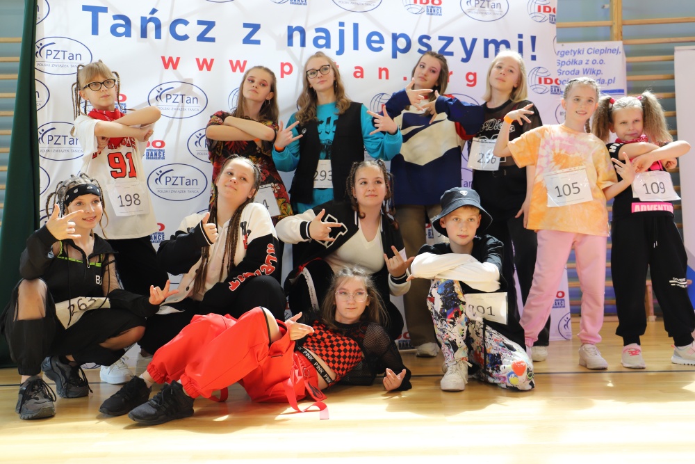 XII Ogólnopolski Turniej Tańca Nowoczesnego Taneczna Środa 2022, grupa taneczna z pucharem na ściance fotograficznej