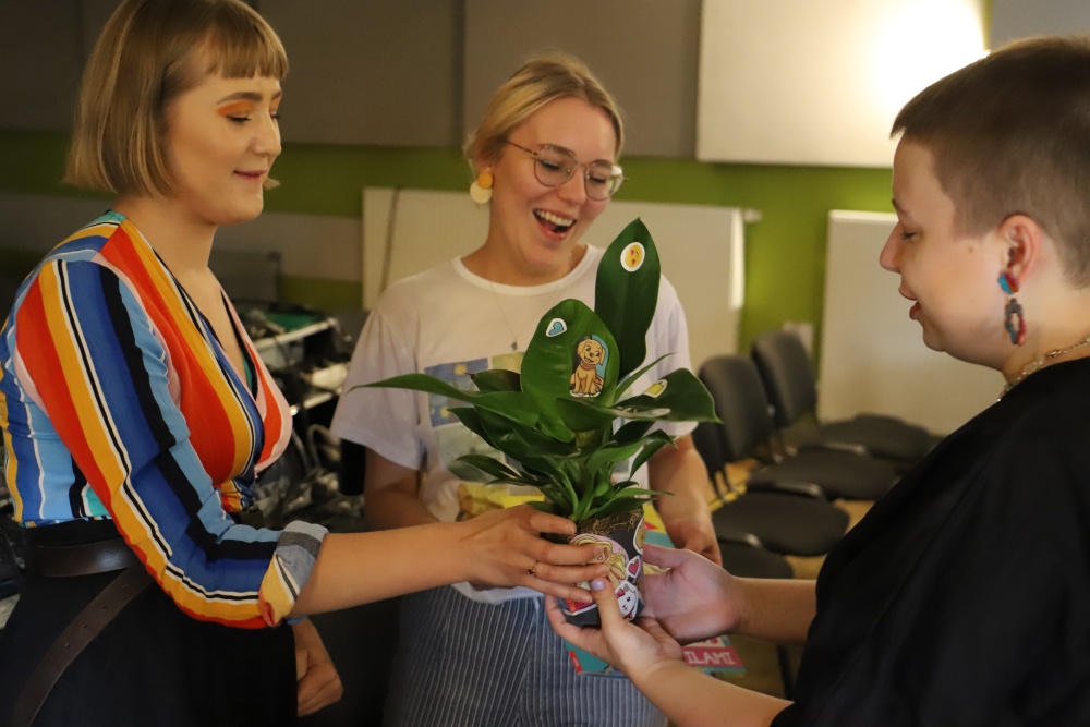 2 dziewczyny gratulują prowadzącej zajęcia, wręczają jej roślinkę w doniczce